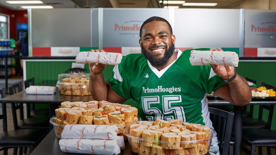 Philadelphia Eagles star Brandon Graham holding sandwiches in a PrimoHoagies location.